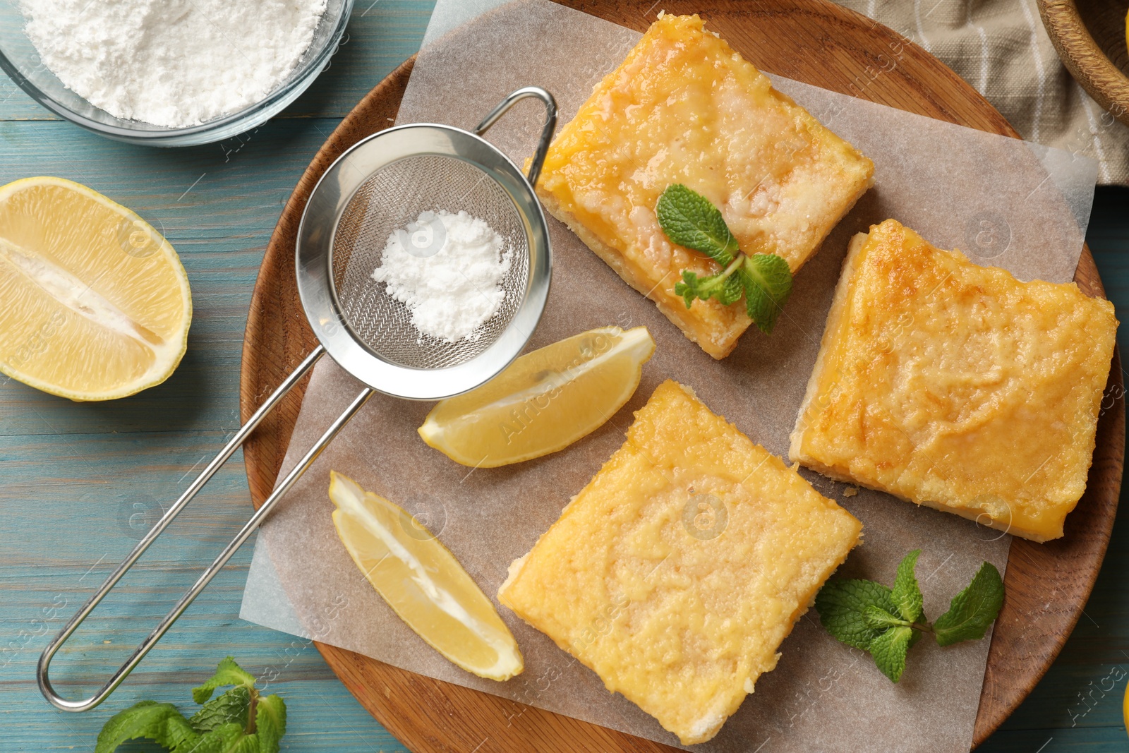 Photo of Tasty lemon bars and mint on light blue wooden table, flat lay