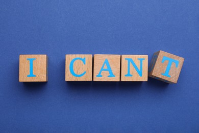 Motivation concept. Changing phrase from I Can't into I Can by removing cube with letter T on blue background, top view