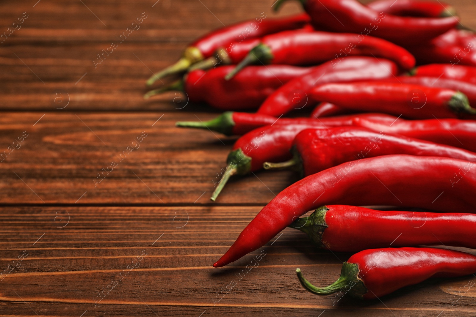 Photo of Fresh red chili peppers on wooden table with space for text