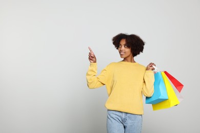 African American woman with shopping bags on light grey background. Space for text