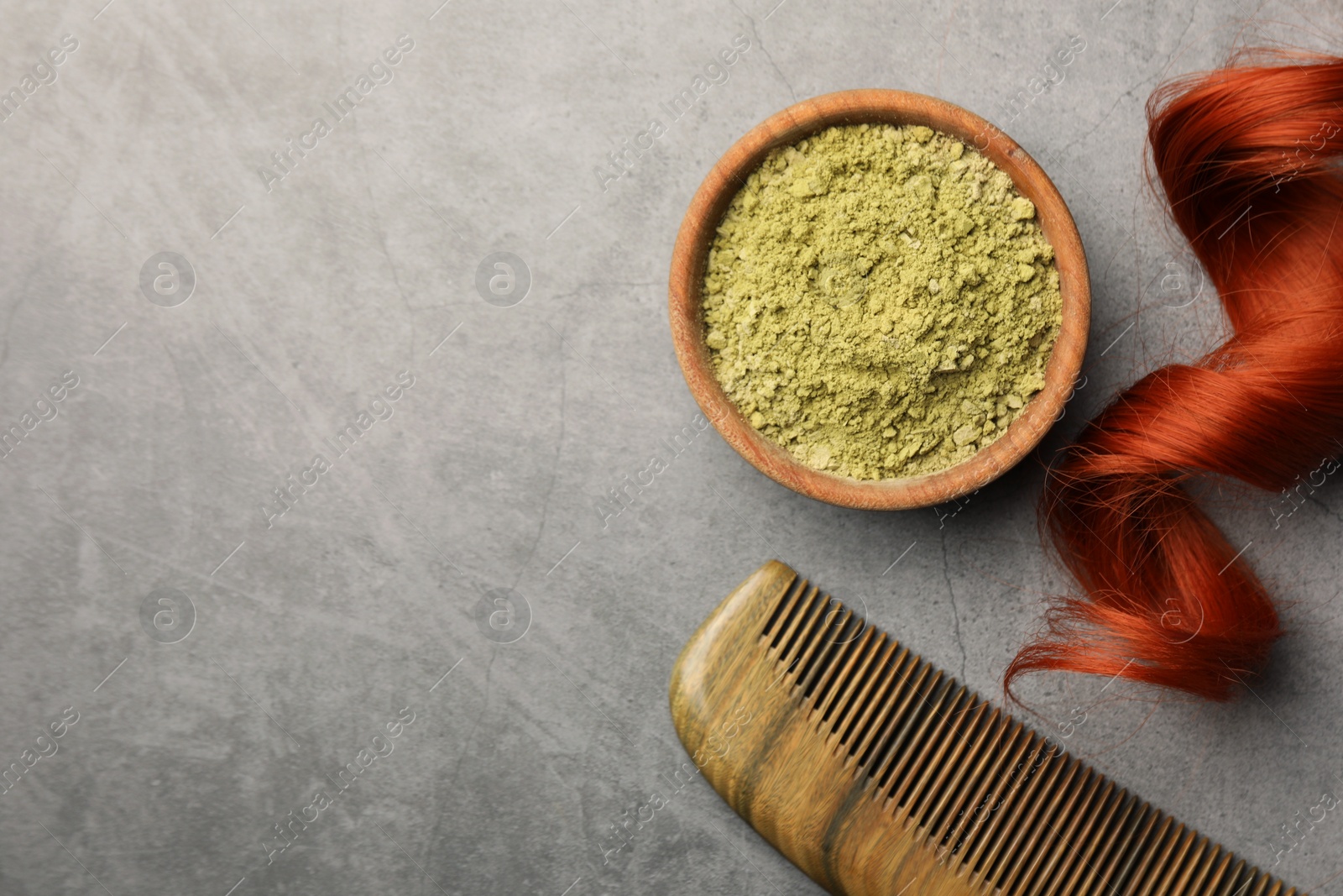 Photo of Red strand, henna powder and comb on grey table, flat lay with space for text. Natural hair coloring