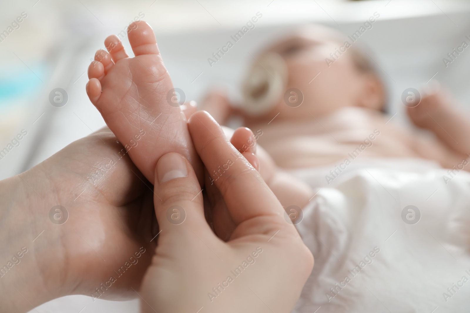 Photo of Mother massaging her cute baby with oil, closeup