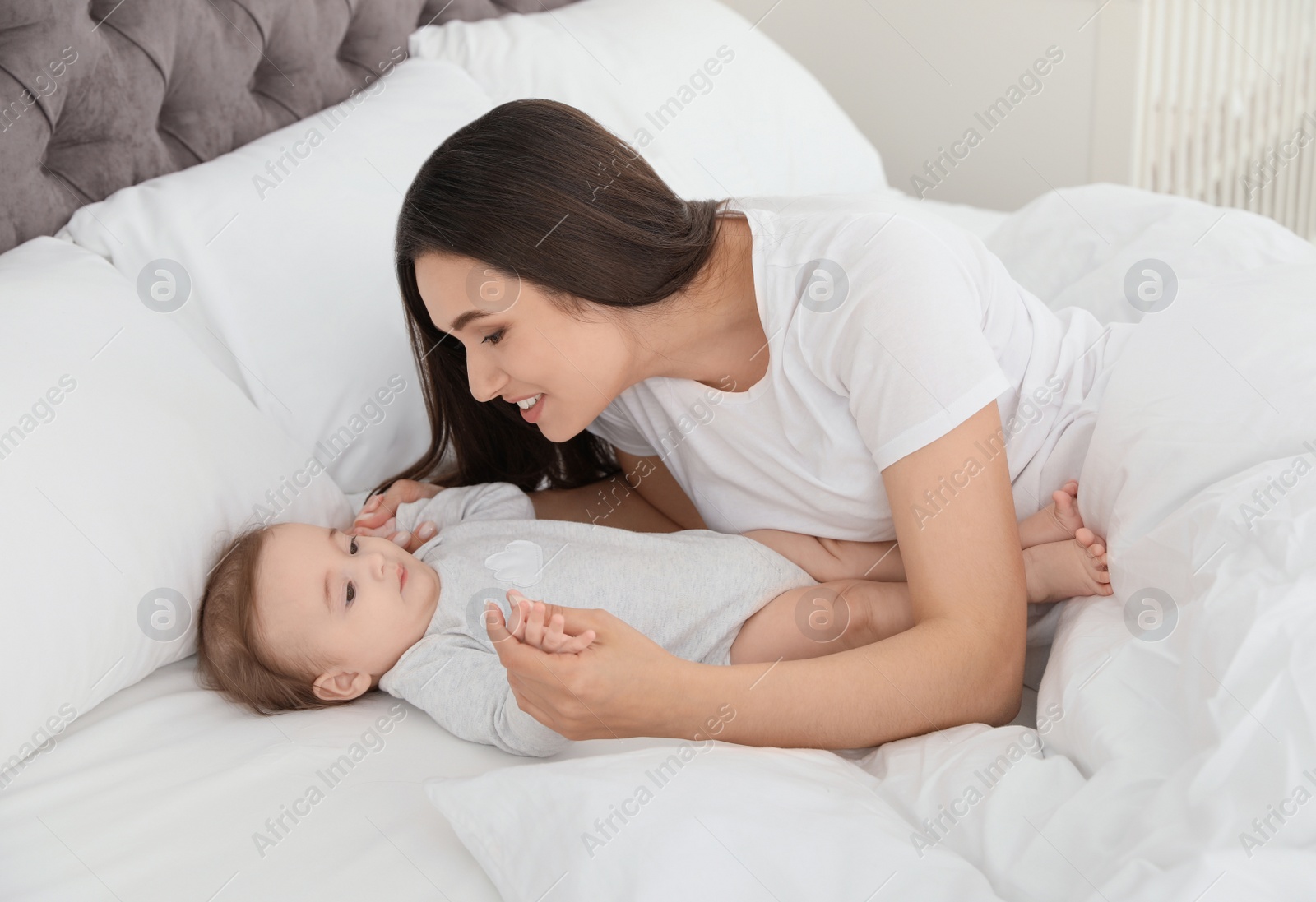 Photo of Portrait of mother with her cute baby lying on bed indoors