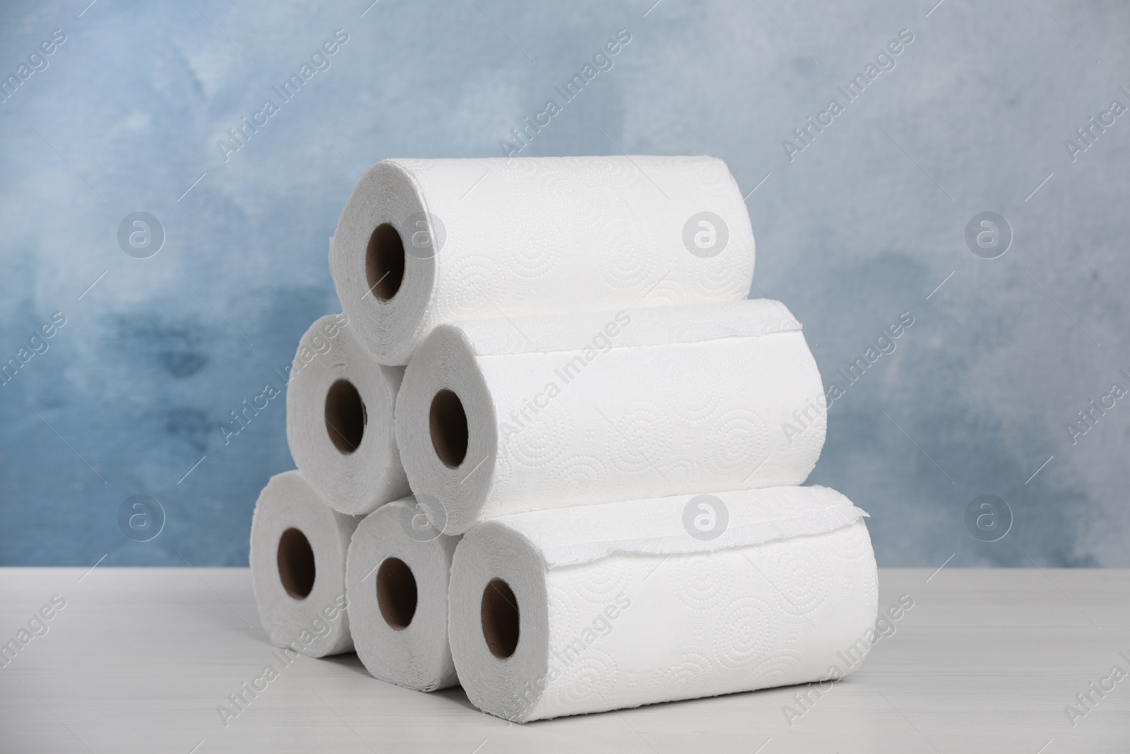 Photo of Many rolls of paper towels on white wooden table