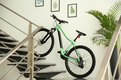 Photo of Modern green bicycle on stairs at home