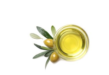 Little bowl with oil, ripe olives and leaves on white background