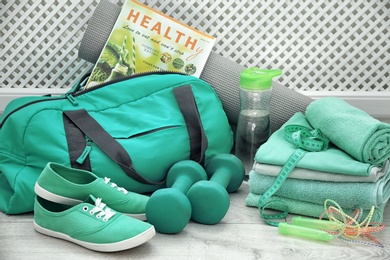 Photo of Sports bag and gym equipment in different mint color shades on floor