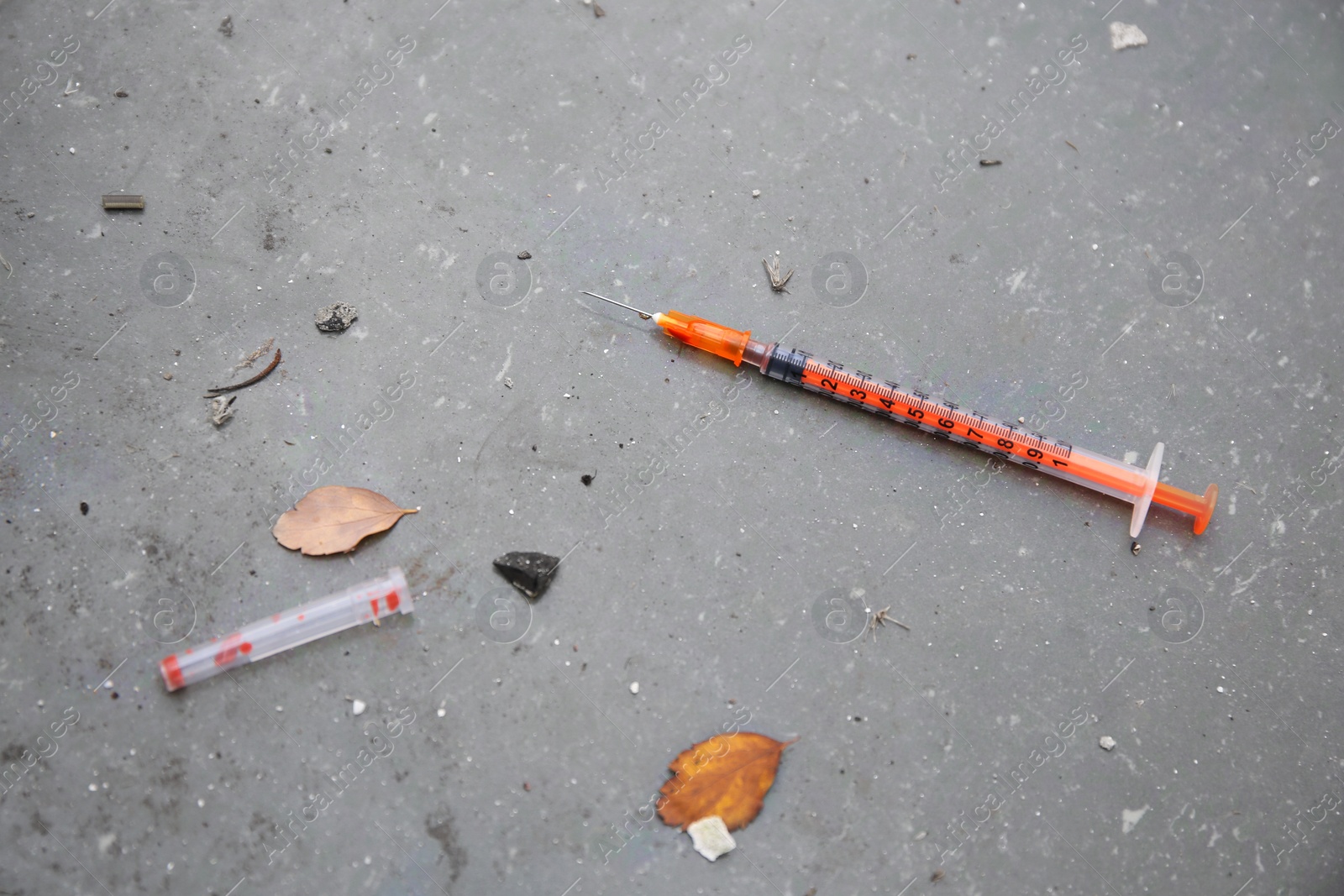 Photo of Disposable syringe with needle on concrete surface outdoors