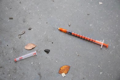 Photo of Disposable syringe with needle on concrete surface outdoors