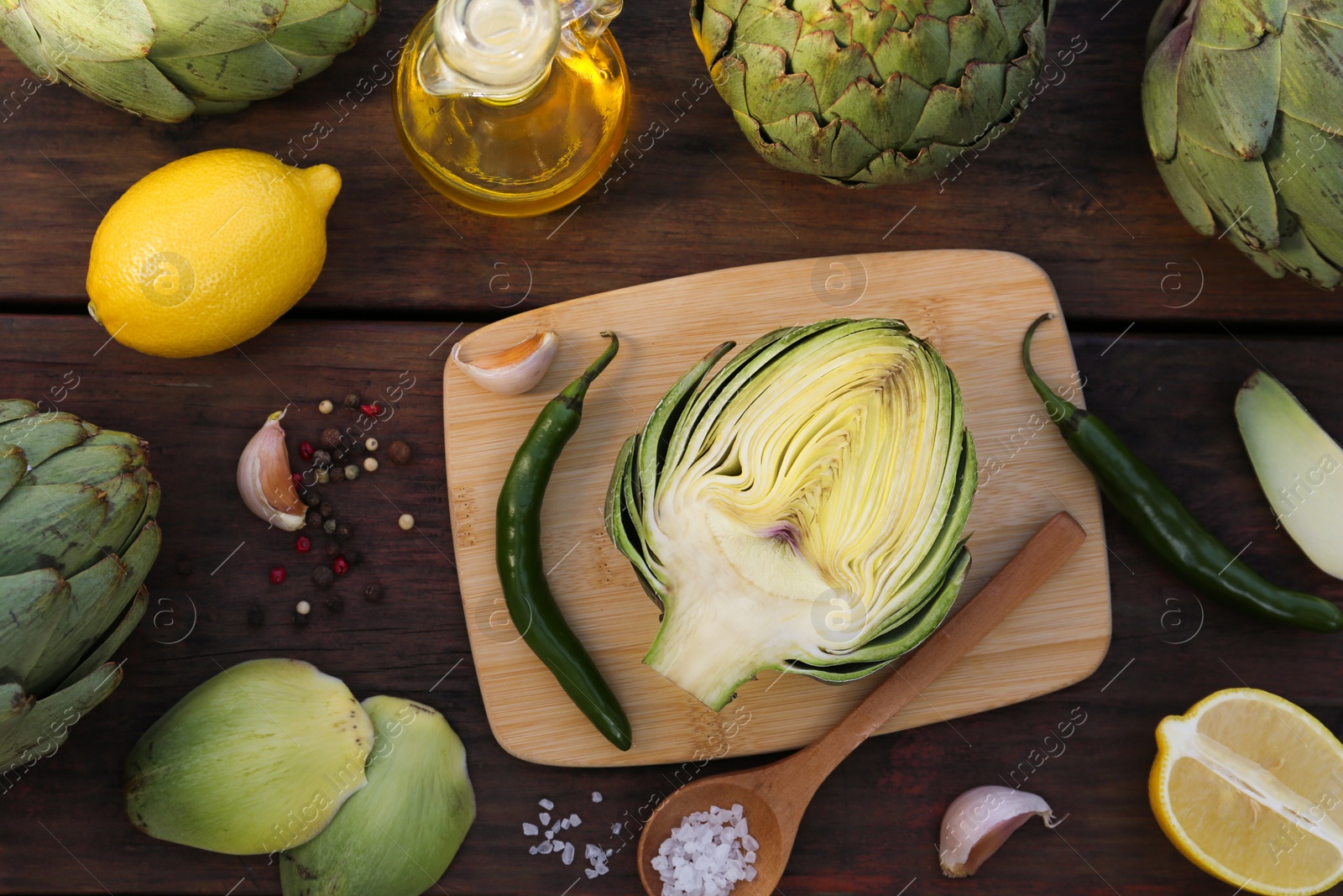 Photo of Artichokes, oil and lemons on wooden table, flat lay