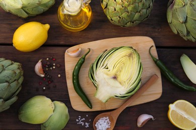Photo of Artichokes, oil and lemons on wooden table, flat lay