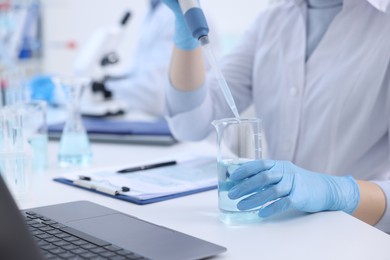 Photo of Scientist dripping sample into beaker in laboratory, closeup