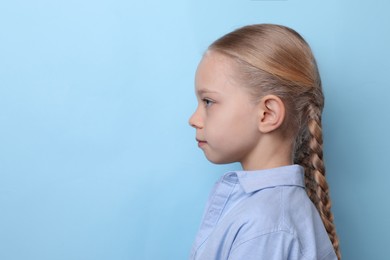 Photo of Profile portrait of cute little girl on light blue background. Space for text
