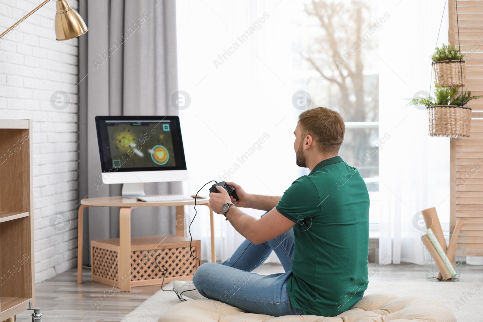 Photo of Young man playing video game at home