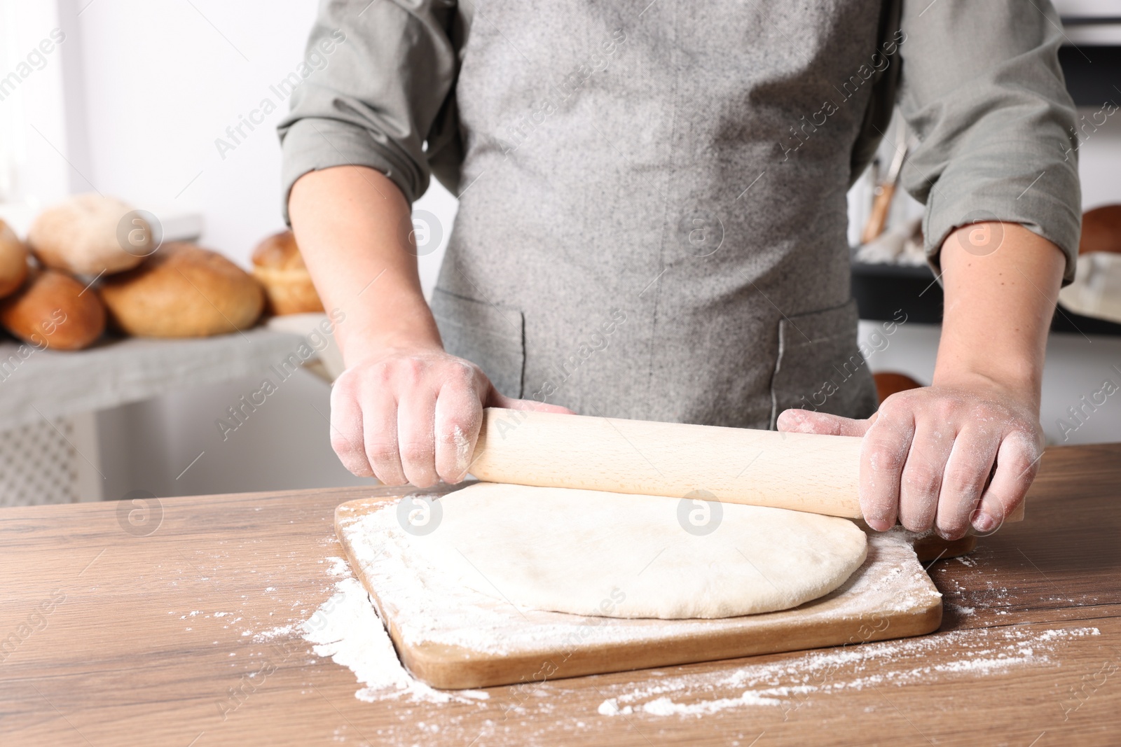 Photo of Man rolling dough at table in kitchen, closeup