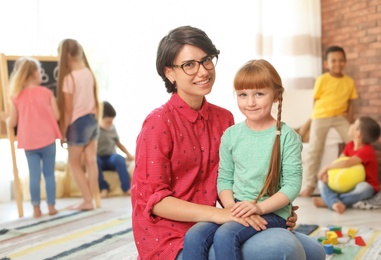 Photo of Young woman with little child indoors. Learning by playing