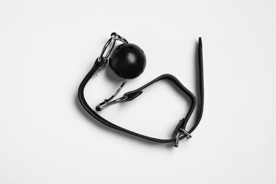 Photo of Black ball gag on white background, top view. Sex toy