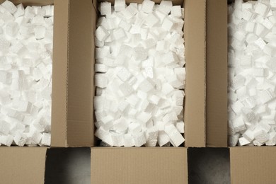 Many open cardboard boxes with pieces of polystyrene foam on grey floor, flat lay
