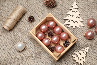Photo of Composition with beautiful Christmas baubles and wooden crate on sacking, above view