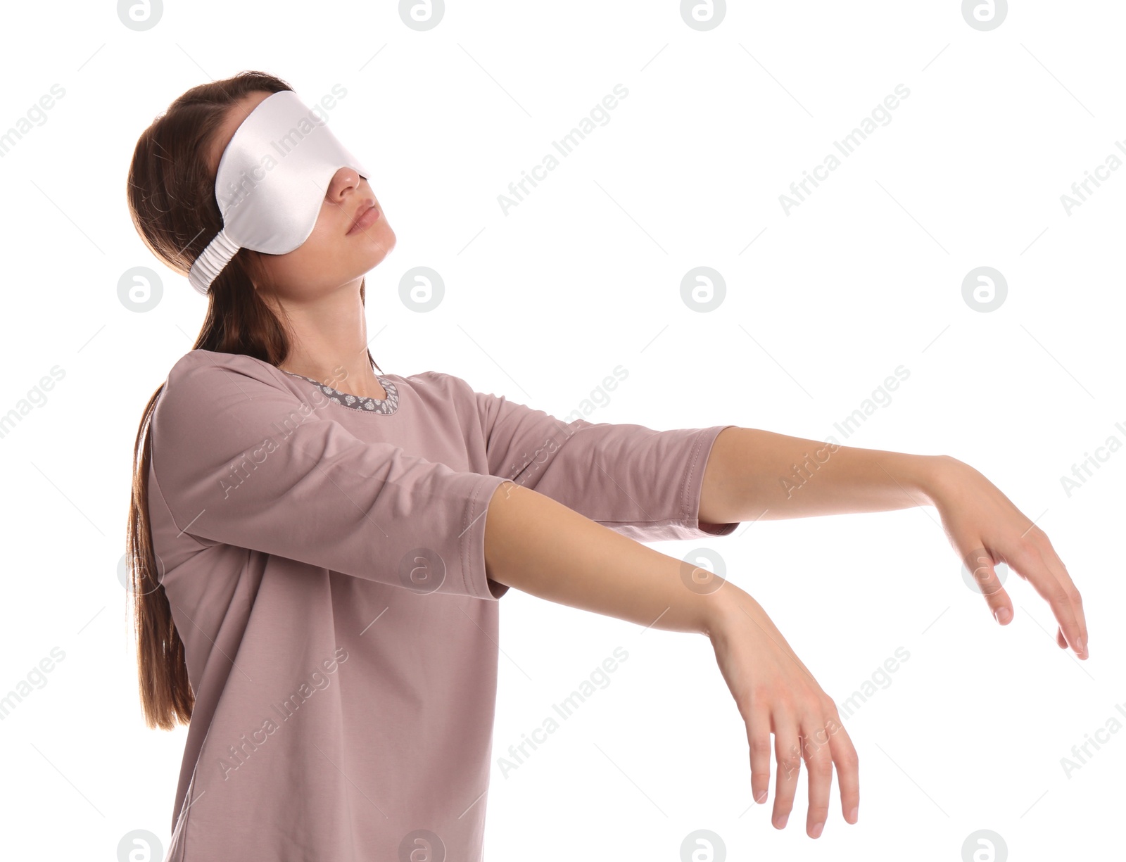 Photo of Young woman wearing pajamas and mask in sleepwalking state on white background