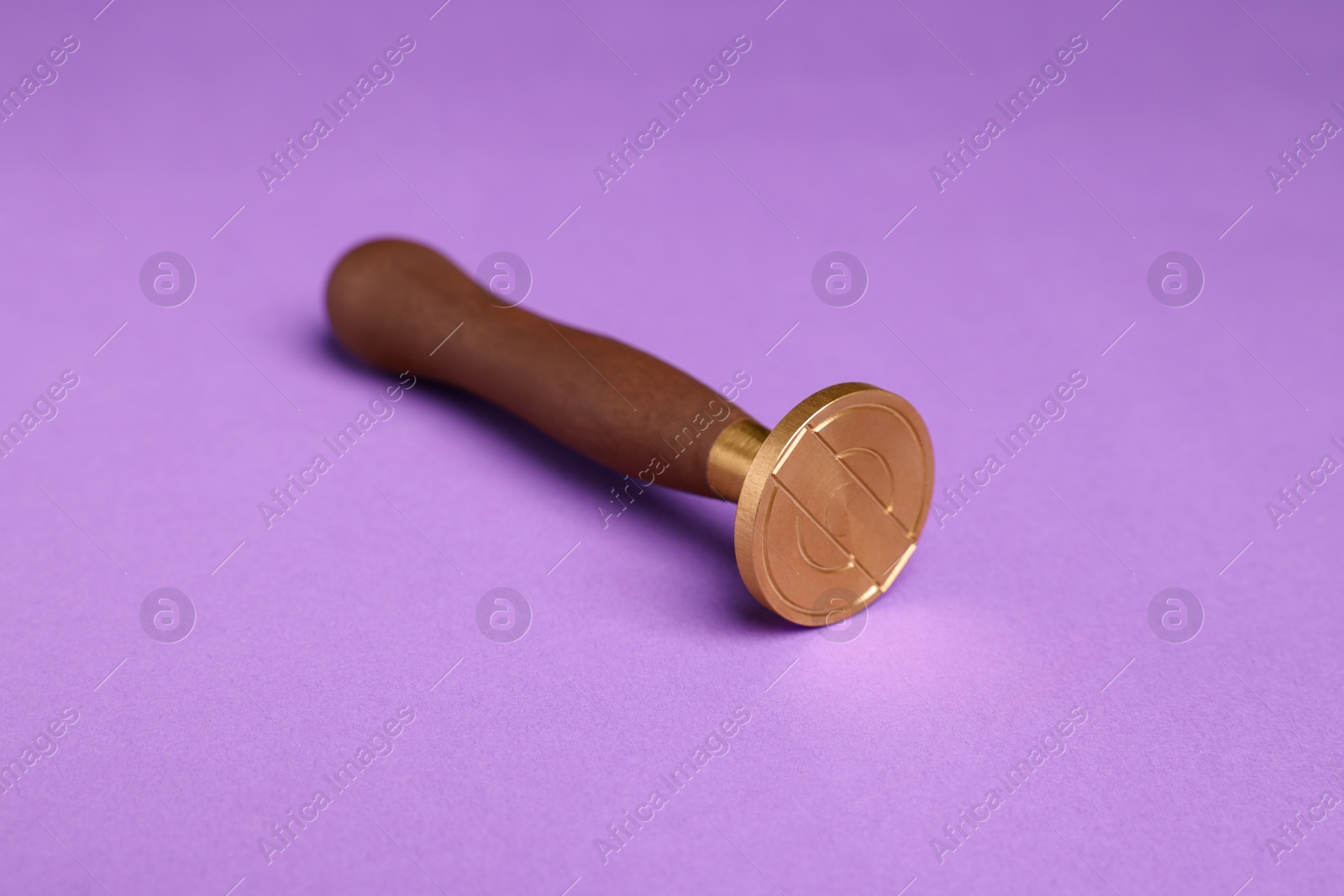 Photo of One stamp tool with wooden handle on purple background, closeup