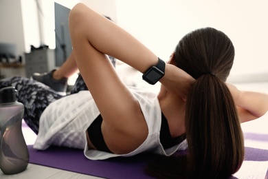 Photo of Woman wearing fitness tracker during training in gym