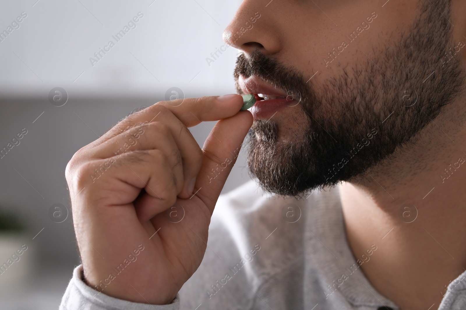 Photo of Man taking antidepressant pill on blurred background, closeup