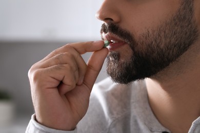 Photo of Man taking antidepressant pill on blurred background, closeup