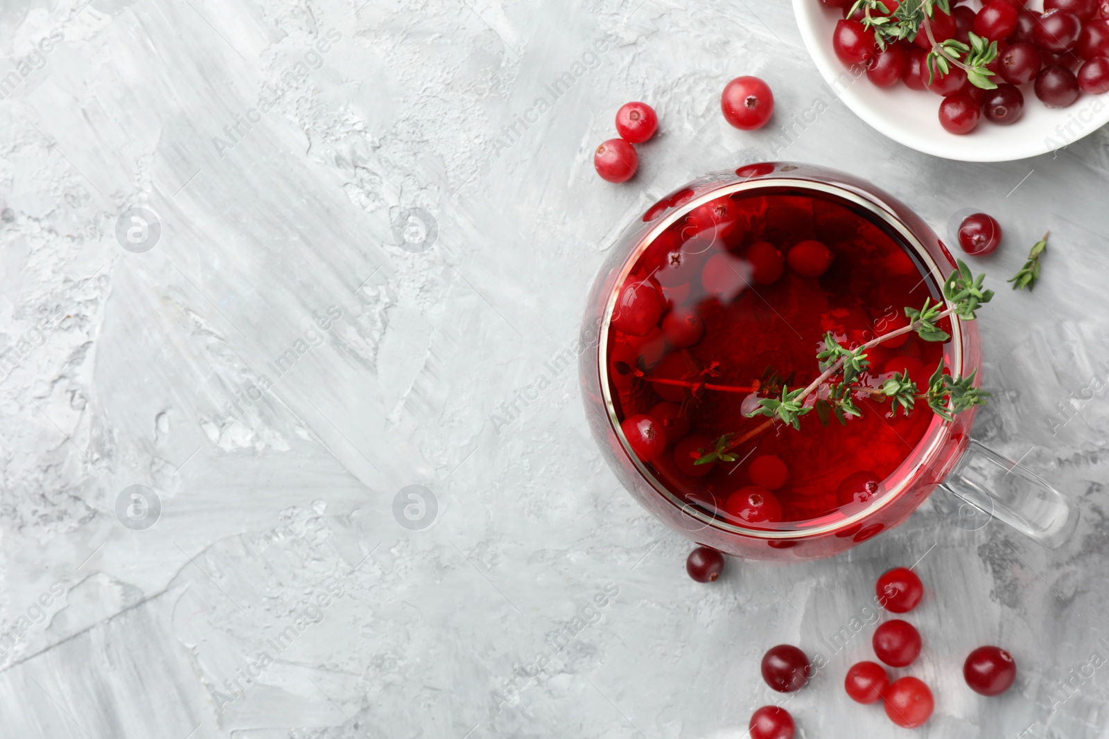 Photo of Delicious cranberry tea with thyme and berries on grey table, flat lay. Space for text