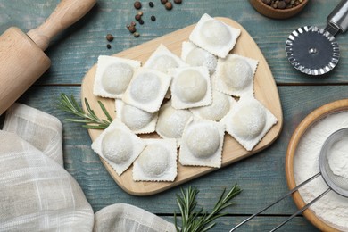 Photo of Homemade uncooked ravioli on blue wooden table, flat lay