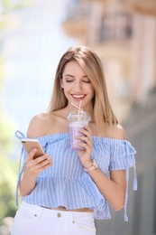 Photo of Young woman with plastic cup of healthy smoothie outdoors