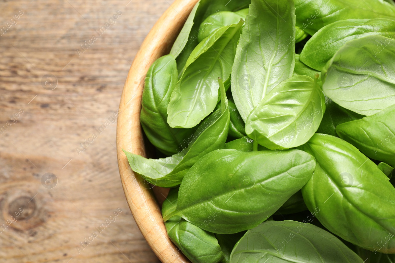 Photo of Fresh basil on wooden table, top view