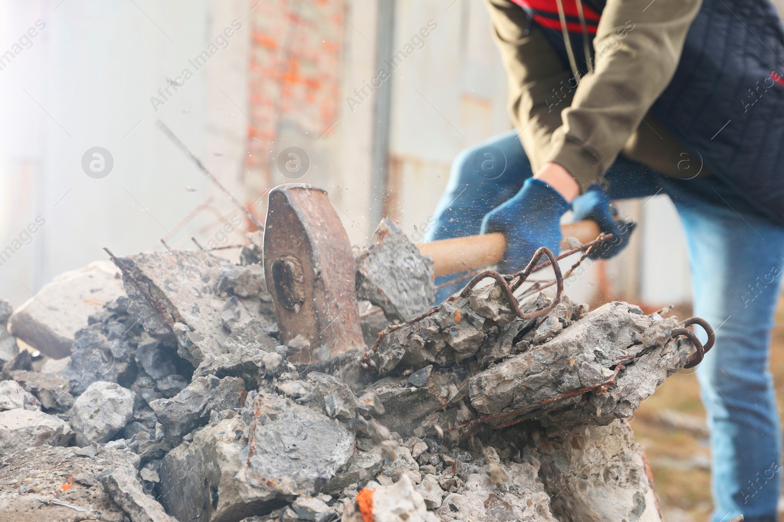 Photo of Man breaking stones with sledgehammer outdoors, closeup