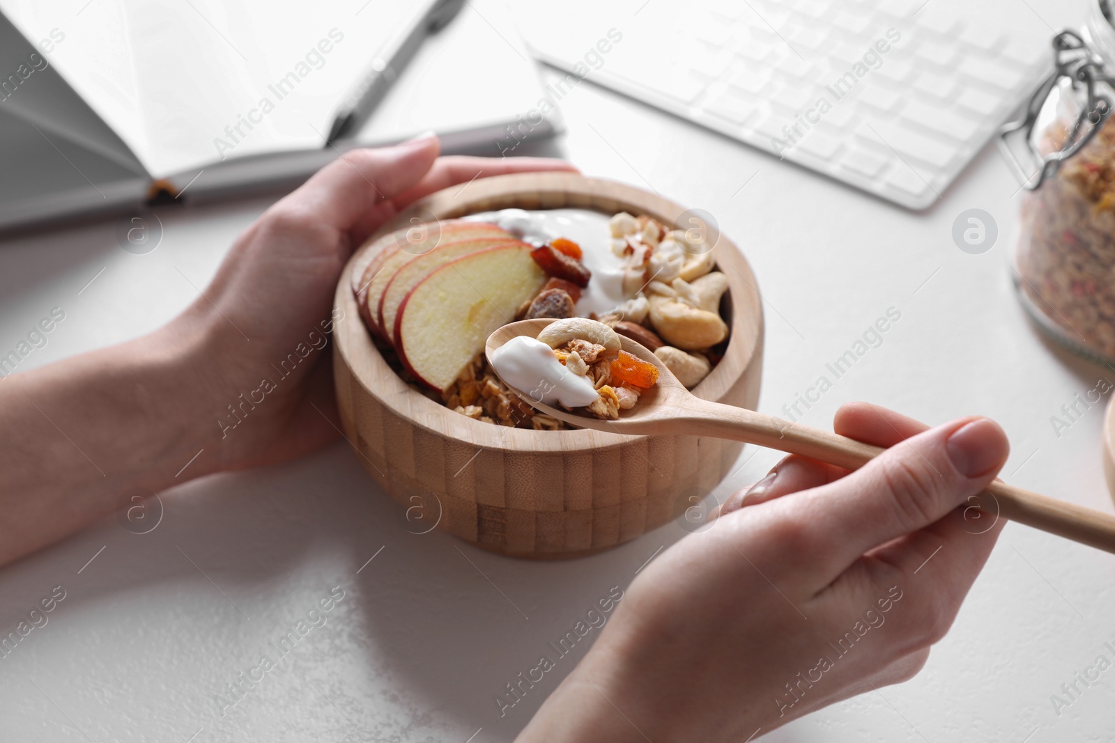 Photo of Woman eating tasty granola at workplace, closeup