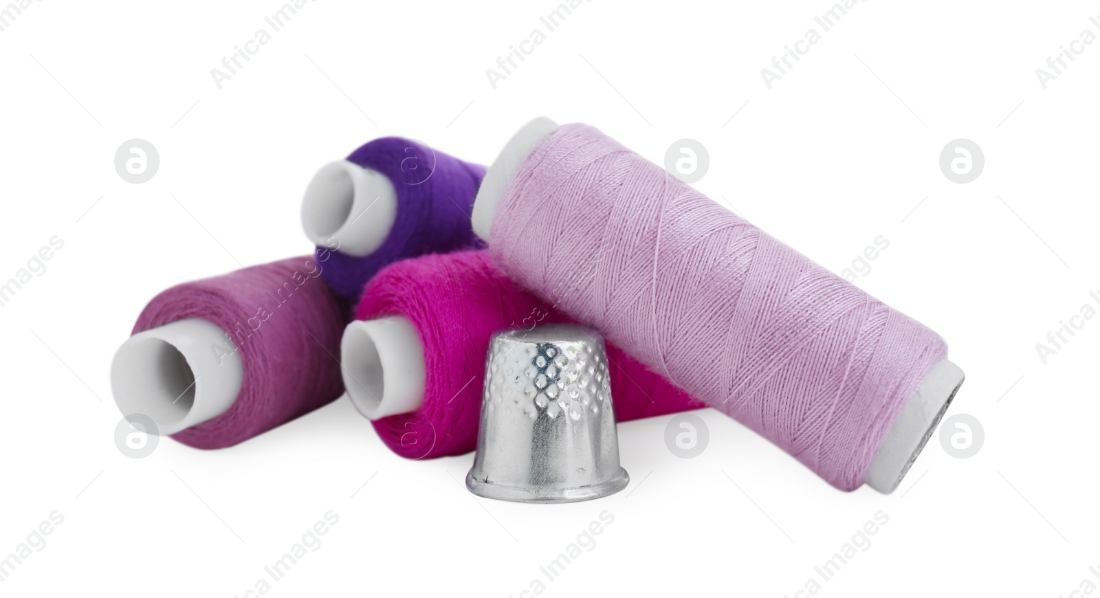 Photo of Thimble and spools of sewing thread isolated on white