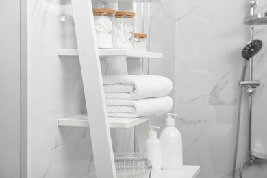 Photo of Stacked bath towels on white shelf in bathroom