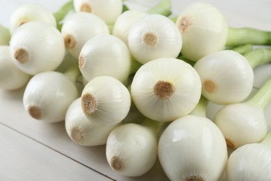 Whole green spring onions on white wooden table, closeup