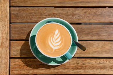 Photo of Cup of aromatic hot coffee and spoon on wooden table, top view