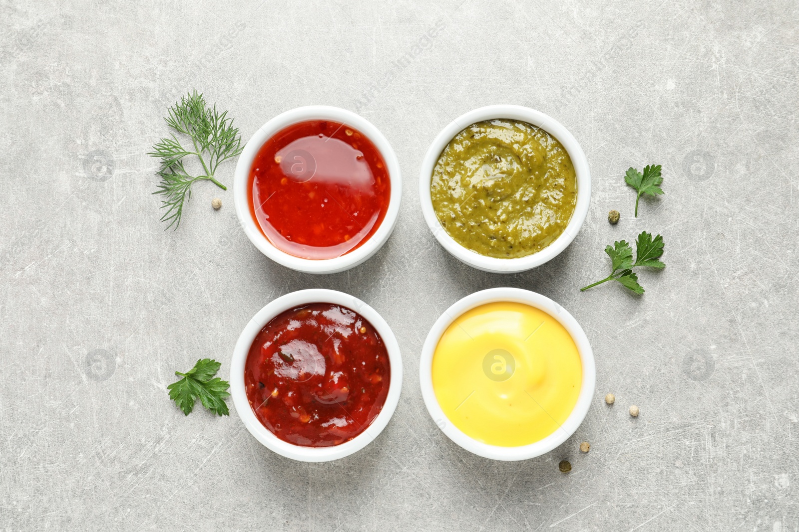 Photo of Set of different delicious sauces on grey table, top view