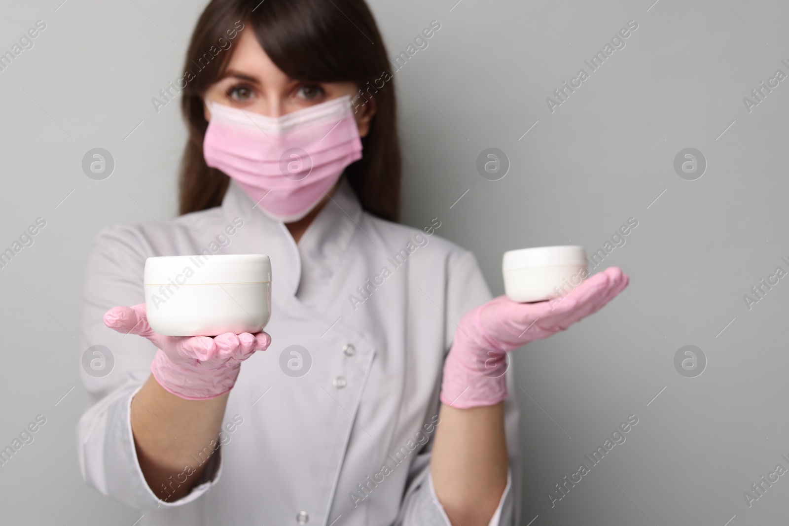 Photo of Cosmetologist with cosmetic products on grey background, selective focus