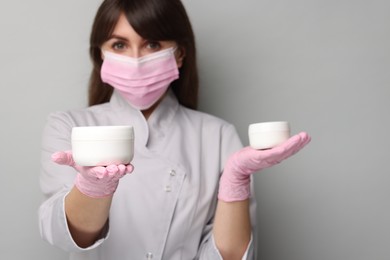 Cosmetologist with cosmetic products on grey background, selective focus