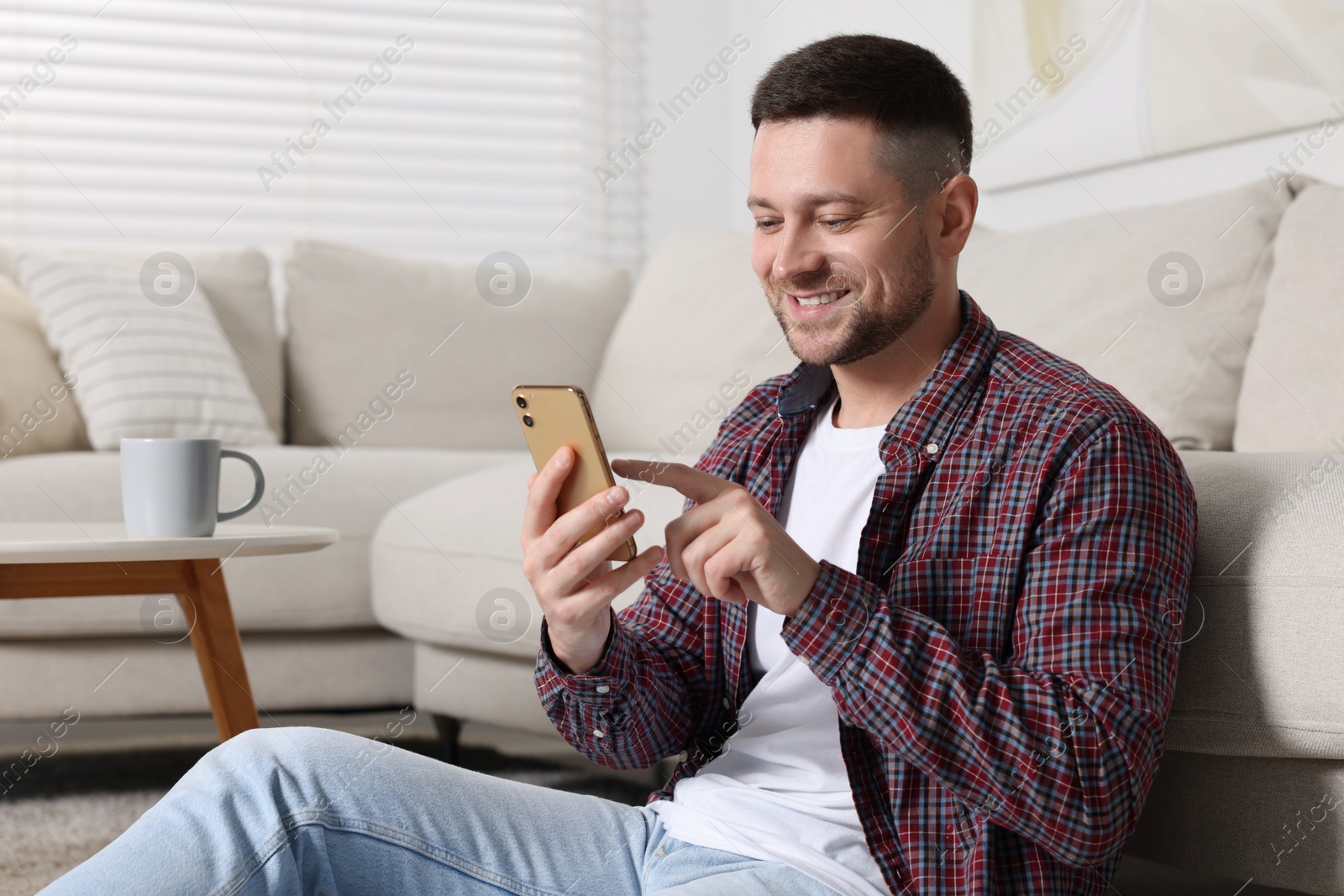 Photo of Handsome man typing message on smartphone at home