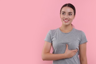 Photo of Beautiful happy woman doing breast self-examination on pink background. Space for text