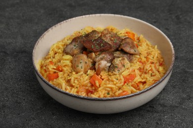 Photo of Delicious pilaf with meat on grey textured table, closeup