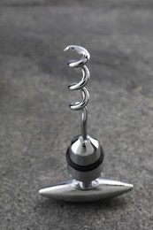 Photo of One metal corkscrew on grey textured table, closeup