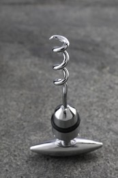 One metal corkscrew on grey textured table, closeup