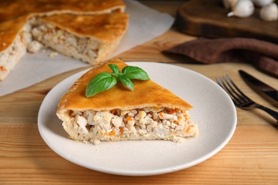 Photo of Slice of delicious meat pie with basil on wooden table