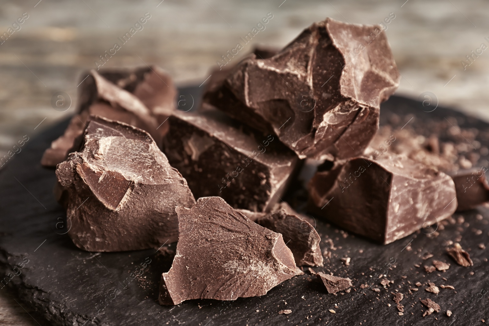 Photo of Delicious dark chocolate on slate plate, closeup