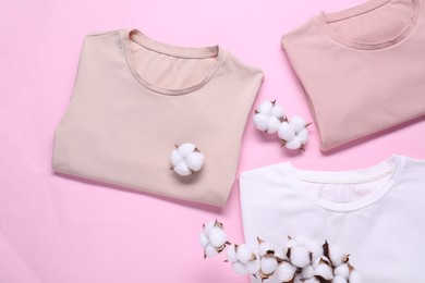 Photo of Cotton branch with fluffy flowers and t-shirts on pink background, flat lay