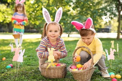 Photo of Cute little children hunting eggs in park. Easter tradition